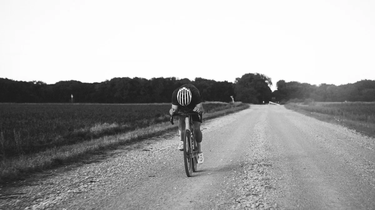 Radsportler allein auf einer geraden Landstraße, Schwarzweiß-Aufnahme